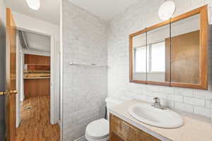 Bathroom with tile walls, vanity, wood finished floors, and a stall shower