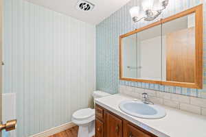 Bathroom featuring vanity, wallpapered walls, and wood finished floors