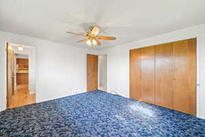 Unfurnished bedroom featuring a textured ceiling, a ceiling fan, carpet floors, and a closet