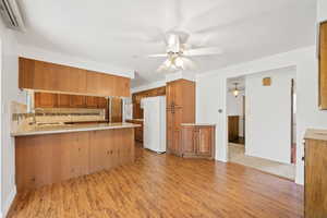 Kitchen featuring light wood-style flooring, tasteful backsplash, a peninsula, and white appliances
