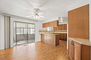Kitchen featuring tasteful backsplash, light stone countertops, light wood-type flooring, and a peninsula