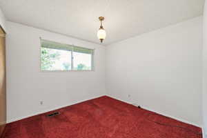Carpeted spare room featuring a textured ceiling and baseboards