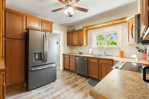 Kitchen with appliances with stainless steel finishes, brown cabinetry, and light countertops