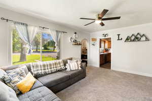 Carpeted living area with a textured ceiling, crown molding, arched walkways, and ceiling fan