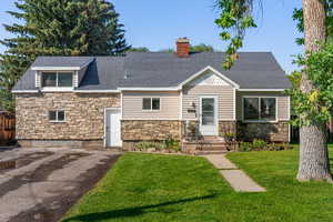 View of front of home featuring stone siding, a shingled roof, and a chimney