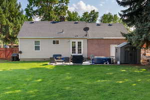 Rear view of house featuring a storage unit, a patio area, a chimney, a shingled roof, and crawl space