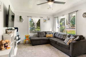 Carpeted living area with a textured ceiling, ornamental molding, and ceiling fan
