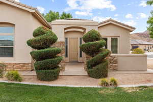 View of exterior entry with stone siding, stucco siding, and a tile roof
