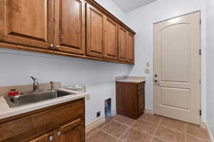 Laundry room featuring dark tile patterned flooring, cabinet space, and hookup for an electric dryer