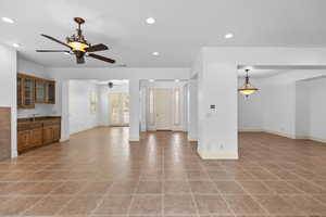 Unfurnished living room featuring recessed lighting, light tile patterned floors, bar with sink, and ceiling fan