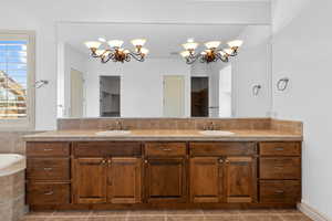 Full bathroom with double vanity, a chandelier, tile patterned flooring, tiled tub, and a walk in shower
