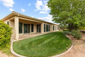 Back of property featuring stucco siding, a lawn, and a patio area