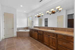Bathroom featuring double vanity, dark tile patterned floors, a bath, a chandelier, and recessed lighting