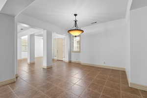 Unfurnished dining area featuring dark tile patterned floors and baseboards