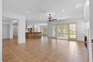 Unfurnished living room with recessed lighting, a glass covered fireplace, a ceiling fan, and light tile patterned flooring