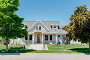 View of front of house featuring a porch, a front yard, and a shingled roof