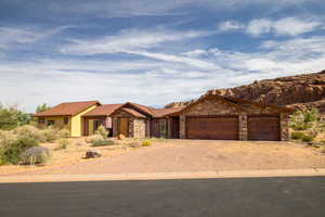 View of front of property with stone siding, a garage, driveway, and a metal roof
