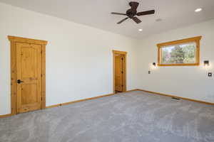Carpeted primary bedroom with ceiling fan and recessed lighting