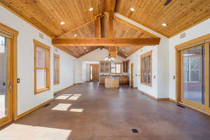 Unfurnished living room featuring finished concrete flooring, a chandelier, a wooden ceiling with exposed beams, and high vaulted ceiling
