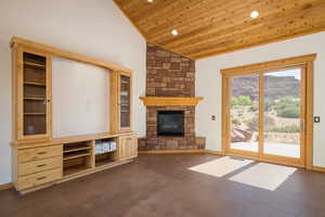 Unfurnished living room featuring wood ceiling, recessed lighting, a stone fireplace, concrete flooring, and a mountain view