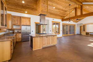 Kitchen with a wood ceiling with exposed beams, high vaulted ceiling, freestanding refrigerator, finished concrete flooring, and a kitchen island