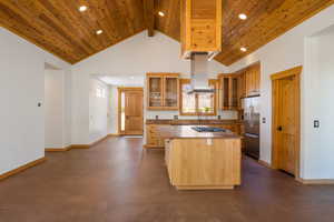 Kitchen with glass insert cabinets, a center island, high vaulted ceiling, a wooden ceiling with exposed beams, and stainless steel appliances