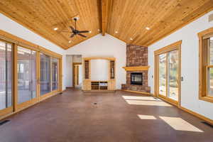 Unfurnished living room featuring a fireplace, high vaulted ceiling, a ceiling fan, and a wooden ceiling with exposed beams