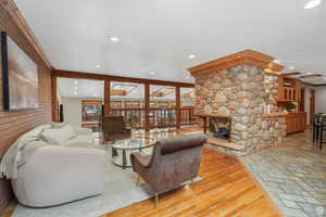 Living room with a stone fireplace, beamed ceiling, and wood-type flooring