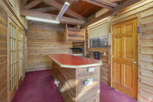 Behind the first set of doors on the left, you'll find a closet for hanging clothes, while the second door just beyond it on the same side has laundry hookups. This space is further enhanced by a beamed ceiling, a wet bar, and rich wood-paneled walls