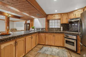 Second kitchen with newer updated countertops, wooden ceiling, stainless steel appliances, beamed ceiling, and backsplash