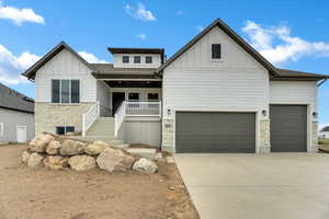 View of front of property featuring stone siding, board and batten siding, covered porch, stairway, and a garage