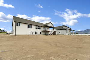 Back of property featuring a balcony, a patio, a mountain view, stairway, and roof with shingles