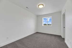 Unfurnished bedroom with dark carpet and baseboards