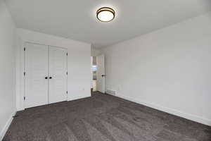 Unfurnished bedroom featuring dark colored carpet and a closet
