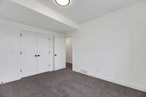 Unfurnished bedroom with dark colored carpet and a closet