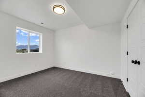 Unfurnished bedroom featuring a closet, dark carpet, and a mountain view