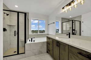 Full bathroom featuring vanity, a garden tub, a shower stall, recessed lighting, and light marble finish floors