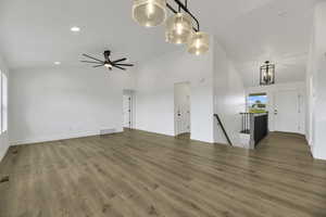 Unfurnished living room featuring light wood-style floors, high vaulted ceiling, recessed lighting, and a chandelier
