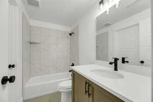 Bathroom with vanity, shower / tub combination, light tile patterned floors, and a textured ceiling