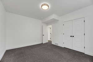 Unfurnished bedroom with dark carpet and a closet