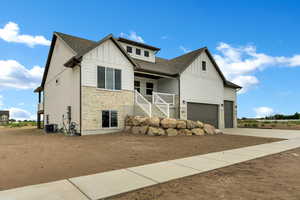 View of front of property featuring stone siding, board and batten siding, driveway, and covered porch