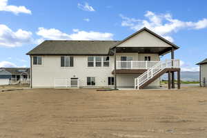 Rear view of house featuring a patio, stairway, a shingled roof, and stucco siding