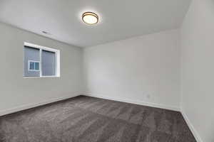 Empty room with dark carpet and baseboards