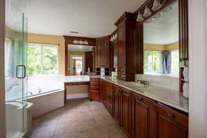 Full bath featuring a bath, vanity, light tile patterned floors, and a shower stall