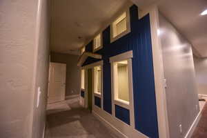 Hallway with dark carpet and a textured wall