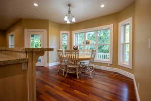 Dining space with dark wood finished floors, recessed lighting, and a chandelier