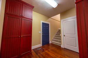 Entrance foyer featuring stairway, a textured ceiling, and dark wood finished floors