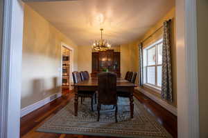 Dining space with dark wood finished floors and a chandelier