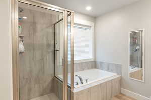 Bathroom with a stall shower, a bath, and wood finished floors