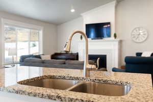 Kitchen with open floor plan, light stone counters, a fireplace, and recessed lighting
